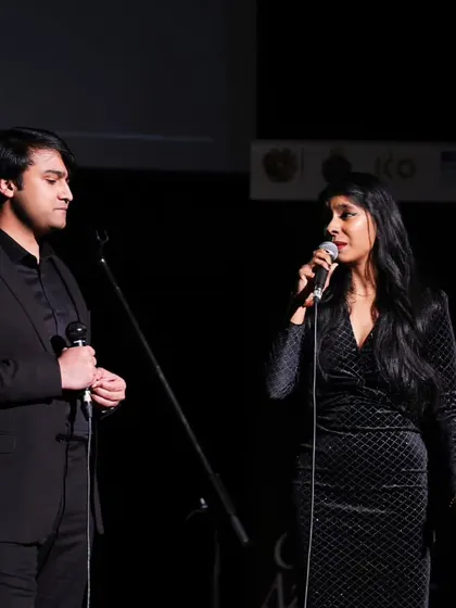 Two hosts engage the audience during the Charles Aznavour musical evening. Our events are professionally compered to ensure a smooth and enjoyable experience for everyone.