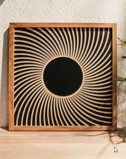 The 'Black Hole' wall art displayed on a shelf. Its hypnotic spiral design in natural wood and black is a striking piece of modern decor.