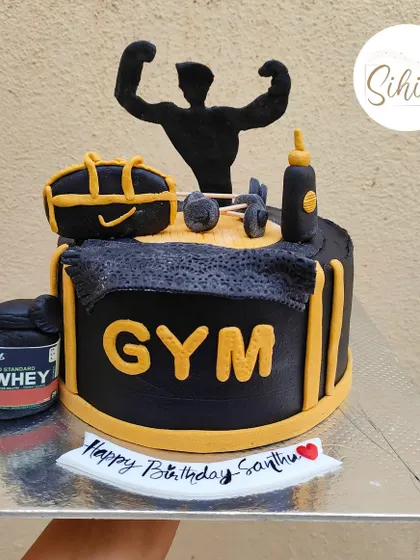 A powerful gym-themed cake for a fitness enthusiast. This black and yellow cake is loaded with fondant details like a whey protein tub, dumbbells, and a bodybuilder silhouette.