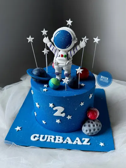Aiming for the sky with this astronaut-themed cake. A simple yet striking design featuring a handcrafted astronaut figurine surrounded by stars and planets.