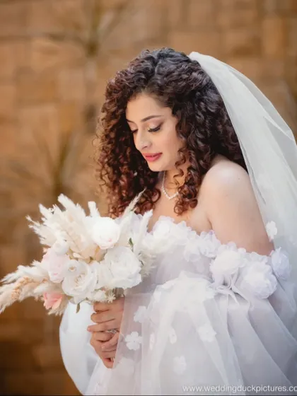 A close-up on the details. The soft, romantic makeup and the delicate textures of her bouquet are a perfect pairing.