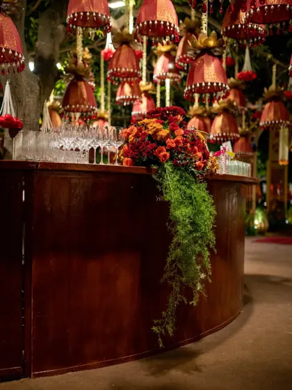 The bar area is also integrated into the theme, with a cascading arrangement of fiery red and orange flowers, set against a backdrop of hanging temple-bell-inspired decor.
