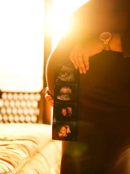 A stunning silhouette shot of the mom-to-be holding her sonogram pictures against the golden light from a window. It’s an artistic and emotional image of her connection to her baby.