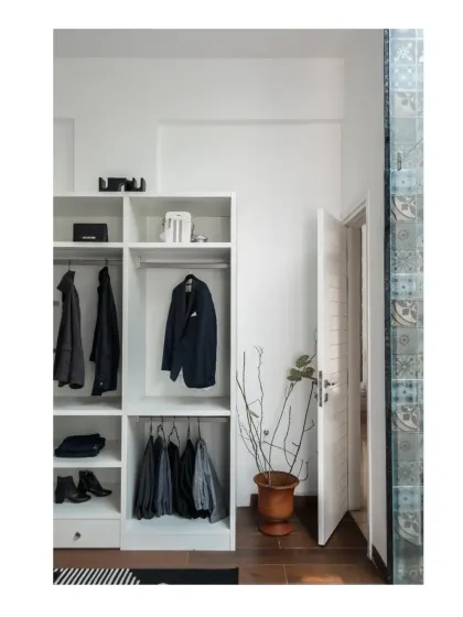 A minimalist open-concept walk-in closet, with clean white shelving and a seamless connection to the en-suite bathroom.