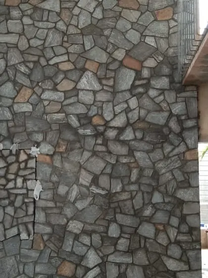 A high interior wall finished with dark grey and brown stone cladding, adding a dramatic and textured effect to the space.