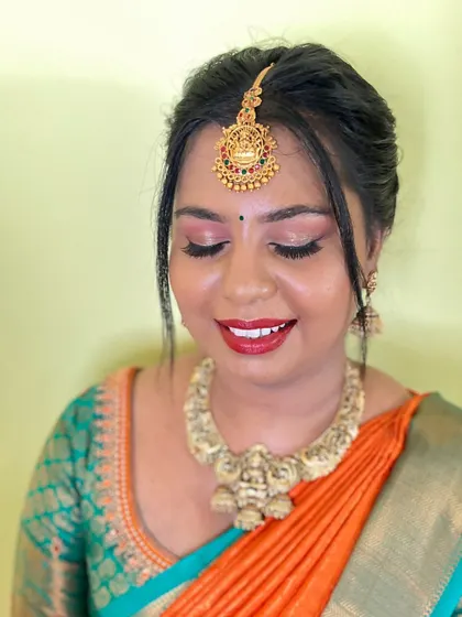 A happy client looking radiant. The soft pink and orange tones in her makeup and saree create a warm and beautiful look.