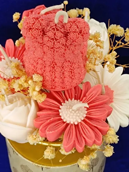 A close-up of a candle bouquet featuring a rose-textured teddy bear.