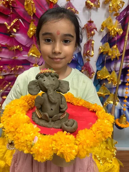 A proud student with her detailed clay Ganesha, complete with a delicate crown and jewelry.