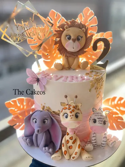 A beautiful jungle animal cake with a soft pink and orange color scheme. This design features a lion, elephant, giraffe, and zebra, all with sweet, friendly faces, perfect for a little girl's birthday.