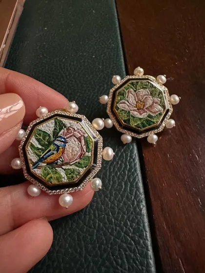 This pair of octagonal earrings features two different micromosaic scenes: a bird on a pink flower and a blooming magnolia. Framed with black enamel, diamonds, and pearls, they tell a story of nature's duality.