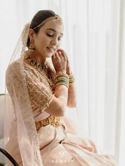 A serene moment as bride Poojita gets ready for her big day. Her custom-embroidered blouse, with its delicate details, adds to the overall elegance and grace of her bridal attire.