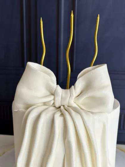 A close-up of the beautifully sculpted white fondant bow on Aasiyah's 17th birthday cake.
