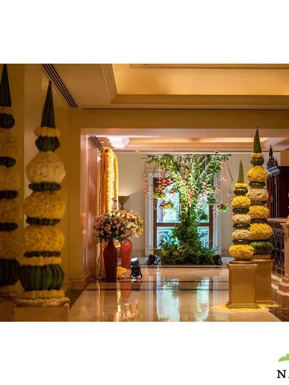 Traditional floral pillars, known as 'thoranams', marking the hallway for a South Indian wedding event. These are crafted from tightly woven flowers and banana leaves, adding an authentic and elegant touch.