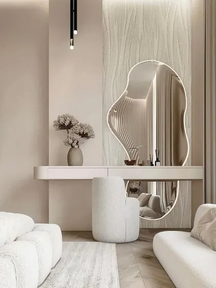 A luxurious dressing table setup featuring a large, amoeba-shaped backlit mirror against a textured wall panel.