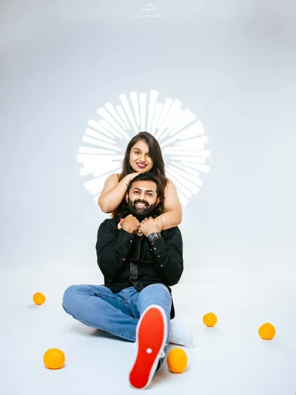 A fun, energetic pose from a studio shoot, with the woman hugging her partner from behind. The bright red sole of his shoe adds a pop of unexpected color.