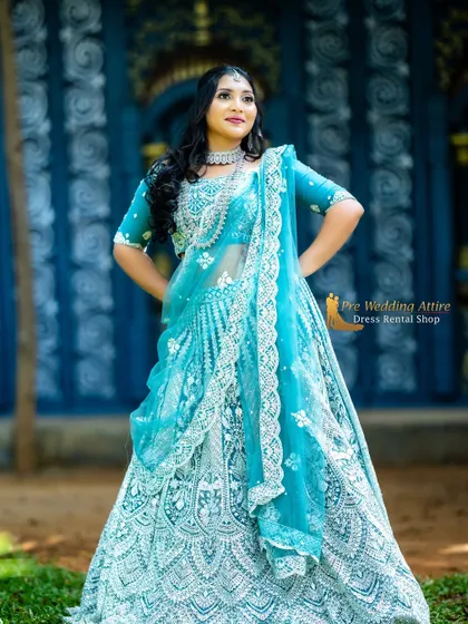 This pose shows the full silhouette of the blue lehenga, with the intricate embroidery covering the entire skirt.
