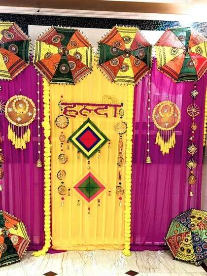 A detailed, straight-on shot of the Haldi backdrop, highlighting the 'Haldi' text in Hindi, dreamcatchers, and colorful umbrellas.