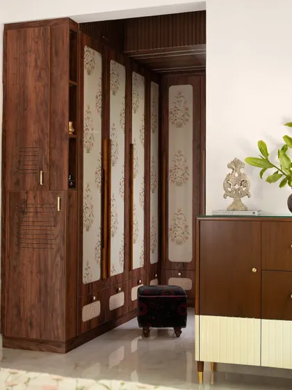 The walk-in wardrobe for the 'Varnika' master suite features floral wallpaper encased in glass on the shutters. This technique adds a delicate, decorative element while protecting the wallpaper.
