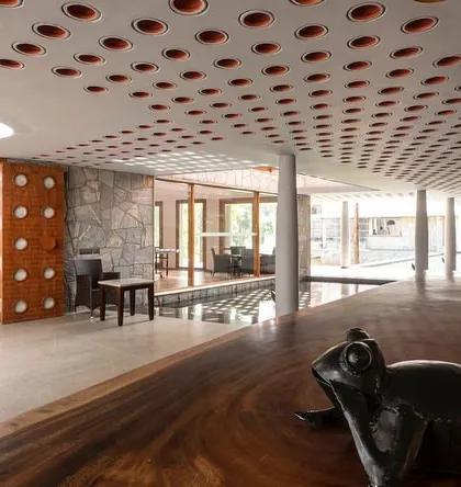 A live-edge wooden countertop brings a raw, organic element into the resort's reception area. This detail contrasts beautifully with the geometric patterns on the ceiling and the rugged stone walls.