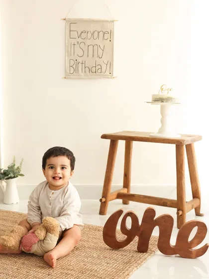One year old and full of smiles. Before the cake smash, I always take some classic portraits to mark the occasion. This simple, rustic setup with a "one" sign is perfect for capturing your baby's personality.