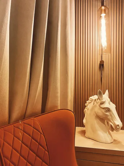 It's all about living in style. A simple corner is elevated with a bold, quilted armchair, a modern horse head sculpture, and an industrial-style pendant light, creating a chic and personal reading nook.