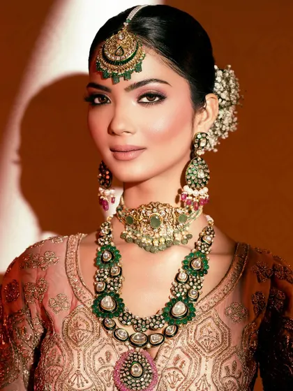 A classic bridal beauty shot with dramatic lighting, highlighting the intricate jewelry and the model's elegant features.