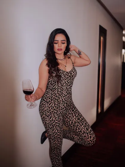 A sophisticated portrait of a model with a glass of red wine. The hotel corridor setting and her elegant pose create a story of luxury and style.