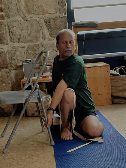 Using a chair and strap to deepen a seated twist. The props provide leverage, allowing for a more complete rotation of the spine while keeping the hips grounded.