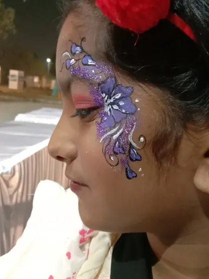 A large, stylized purple flower with white accents and glitter, covering the side of the face. A bold and beautiful choice for kids and adults alike.