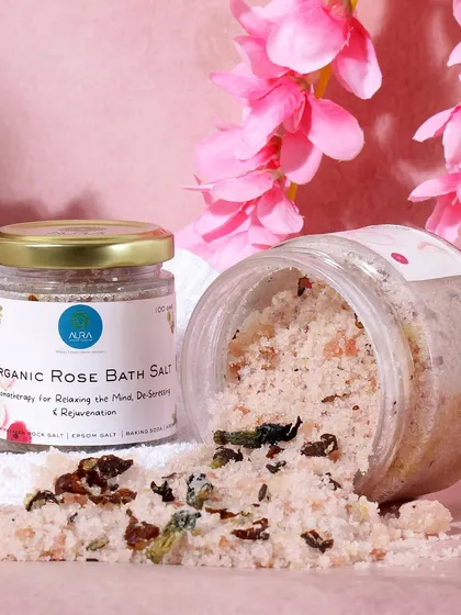 A vibrant and luxurious shot of organic rose bath salts. The bright pink flowers and clean white towel create a visually refreshing and pampering scene, highlighting the product's floral essence.