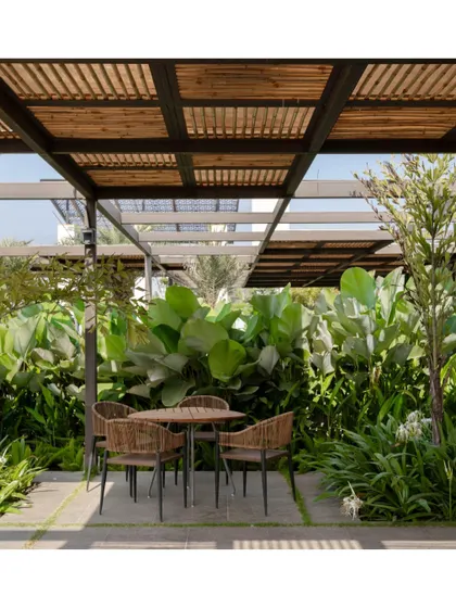 Another view of the outdoor seating area at Brigade Oasis, nestled within dense tropical foliage. The design prioritizes creating comfortable, human scaled spaces that are integrated with nature.