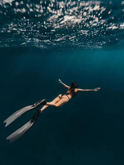 A freediver glides into the deep blue of the Caribbean Sea. The image conveys a sense of freedom and belonging in the vastness of the ocean.