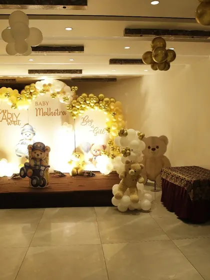 A wider view of the teddy bear baby shower stage, showing the full balloon arch and additional decor elements in the room.