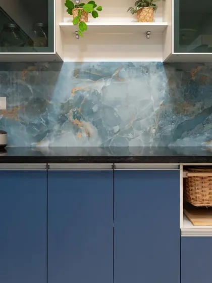 This bold blue kitchen features a stunning blue marble-patterned backsplash. The open niche with a wicker basket adds a natural, rustic touch.
