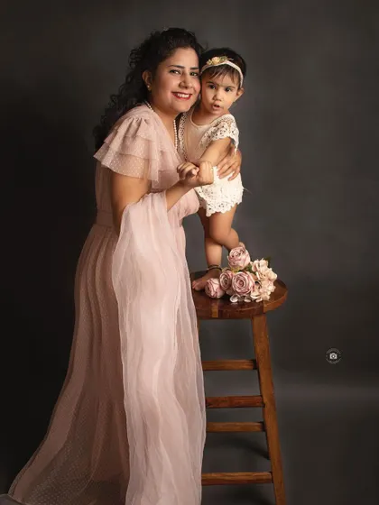 A playful and loving moment between a mother and her daughter. Her daughter standing on the stool adds a fun and dynamic element to the portrait.