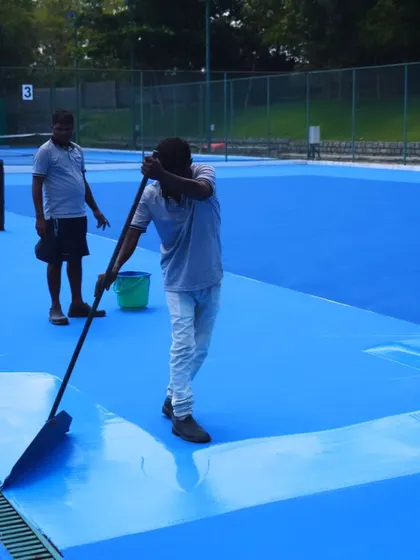 Behind every perfect court is a dedicated team. Here, our grounds crew works diligently to apply the final layers of the acrylic surface, ensuring a flawless finish for our players.