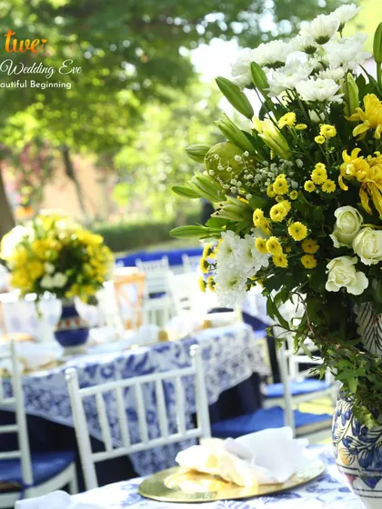 Guest table setting for the Tuscan luncheon, with blue and white printed tablecloths and fresh yellow floral centerpieces.