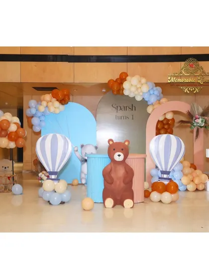 A charming teddy bear and hot air balloon theme for a first birthday, using a soft pastel color palette.
