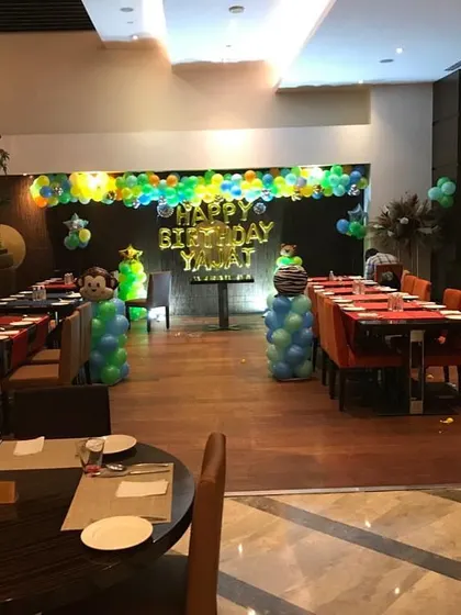 A simple jungle-themed birthday setup in a restaurant, with monkey-themed balloon columns.