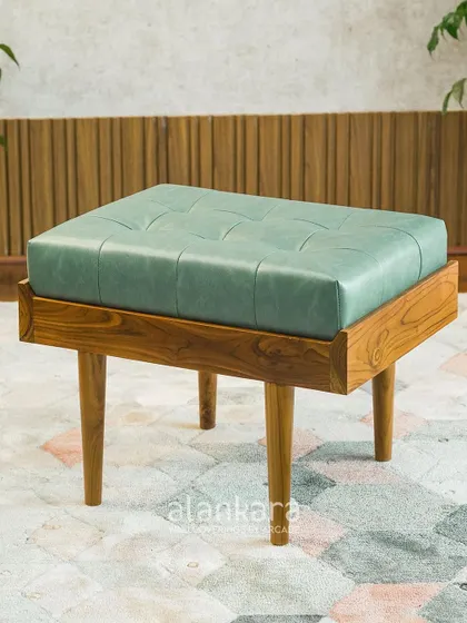 The Colmar stool, crafted from solid teak wood and upholstered in a beautiful seafoam green leatherette. The tufted top adds a touch of classic elegance.