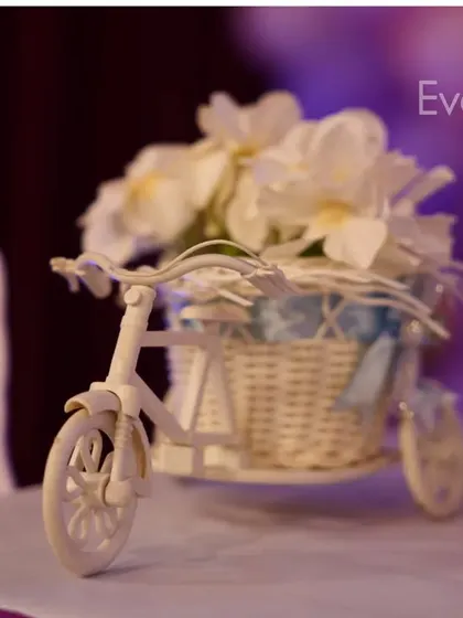 A charming miniature tricycle with a basket of flowers. Small decorative props like this add a touch of elegance and detail to cake tables or guest tables.