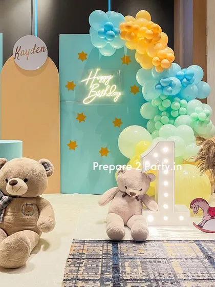 A close-up of the pastel-themed first birthday decor, focusing on the "Happy Birthday" neon sign, the light-up number "1", and the adorable teddy bears.