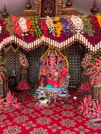 For religious ceremonies like Ganesh Chaturthi or pre-wedding poojas, I create beautiful and respectful decorations. This setup features a grand floral pandal for the Ganesha idol, with vibrant flowers and a traditional red carpet.