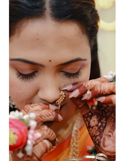 A close-up of the bride adjusting her nose ring, a delicate moment from her Haldi.