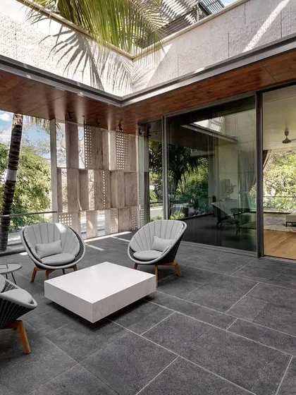 A terrace at the Aqua Grid house opens directly from the bedroom. This space is sheltered by a skylight and surrounded by lush greenery, acting as a private outdoor room.