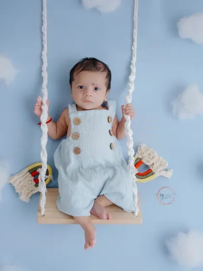 A wider angle of the cloud swing setup, showing the full composition and the baby's adorable, relaxed pose.