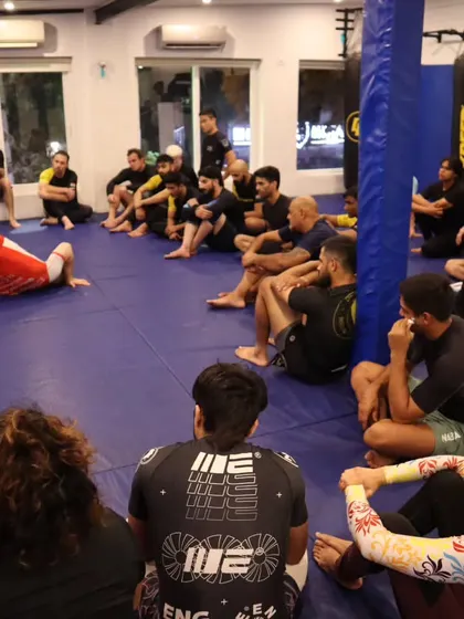 Students watching intently as a complex sweep is demonstrated during the seminar. The focus here is on absorbing the concepts of leverage and positioning from a top-level practitioner.