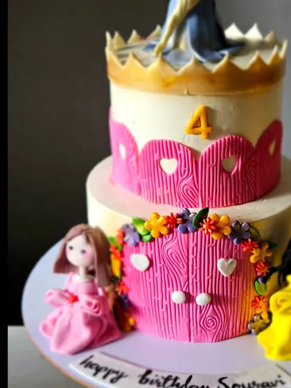 A close-up of the princess castle cake, focusing on the handmade princess figurines at the base.