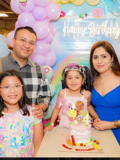 A family of four celebrates their daughter's 4th birthday with a Candyland-themed cake.