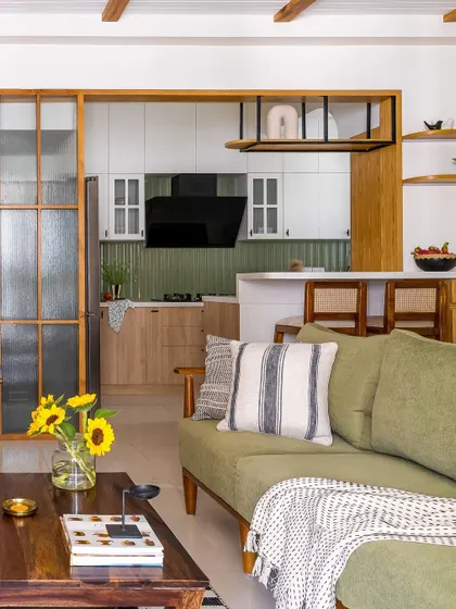 From this angle, you can see how the living room, kitchen, and dining area flow together. The consistent use of green, wood, and cane creates a cohesive theme of warmth and earthiness throughout the home.